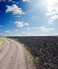 Image showing rural road near black ploughed field