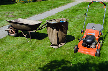 Image showing mower and wheelbarrow to throw the grass 