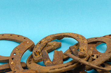 Image showing stack old retro rusty horseshoe blue background 