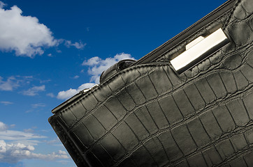Image showing A black business bag on background of sky and clouds