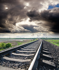 Image showing view to railroad goes to horizon under cloudy sky with sun