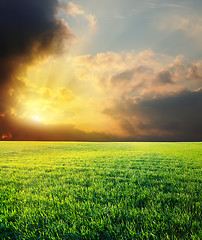 Image showing sunset in dramatic sky over green field