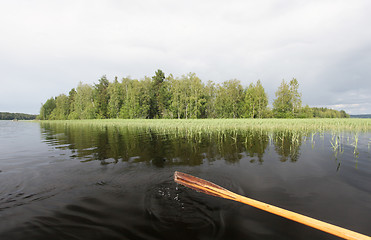 Image showing wooden paddle with water drops against summer lake