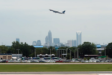 Image showing Commercial jet in the air with city skyline in the background.