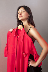 Image showing woman which tries on red shirt in shop