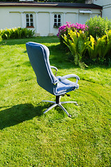 Image showing blue office chair in sunny meadow 