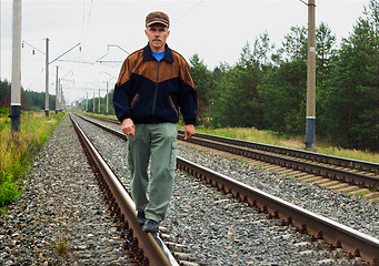 Image showing An elderly man walking on tracks