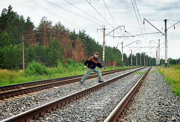 Image showing An elderly man crosses a railway embankment