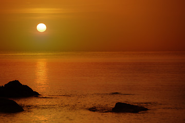 Image showing Orange sunset over the sea with rocks