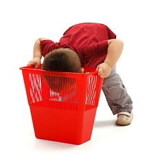 Image showing Little boy looking deep into garbage bin