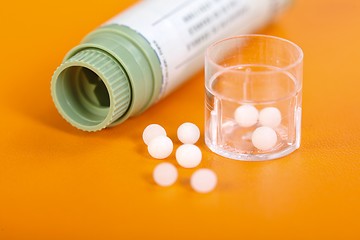 Image showing Homeopathic pills, container on orange