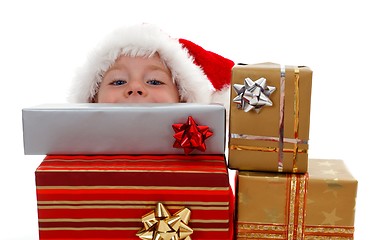 Image showing Young boy peeking above gifts