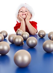 Image showing Little boy sitting behind Christmas ornaments