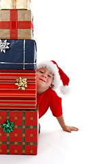 Image showing Young boy smiling behind presents