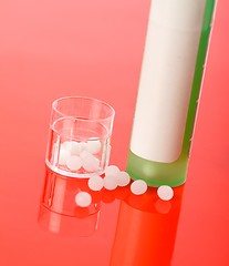 Image showing Homeopathic pills and container on red