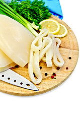 Image showing Squid with lemon and knife on a round board