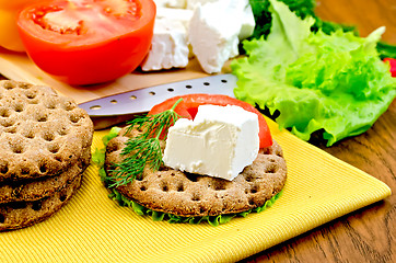 Image showing Feta cheese and tomato on a round bread with a knife