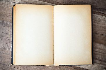 Image showing open old book on a wooden surface 