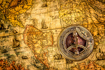 Image showing Vintage compass lies on an ancient world map