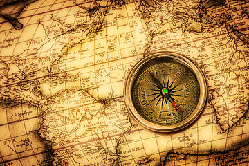 Image showing Vintage compass lies on an ancient world map.