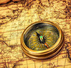 Image showing Vintage compass lies on an ancient world map.