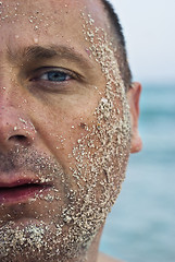 Image showing half face covered with sand