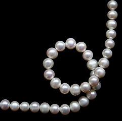 Image showing White pearls on the black silk as background 