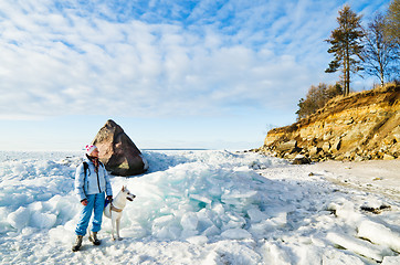 Image showing Woman with a dog walk on a sunny winter day on the coast of the 