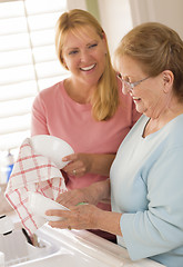 Image showing Senior Adult Woman and Young Daughter Talking in Kitchen