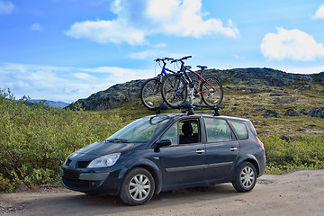 Image showing two bicycles mounted on roof of car against sky