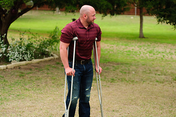 Image showing Muscular bald man on crutches