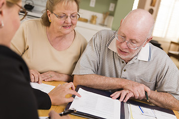 Image showing Senior Adult Couple Going Over Papers in Their Home with Agent