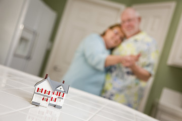 Image showing Senior Adult Couple Gazing Over Small Model Home on Counter