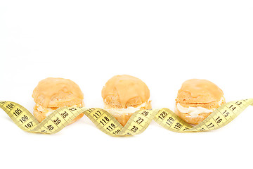 Image showing concept of slimming, caramel cakes with measuring tape