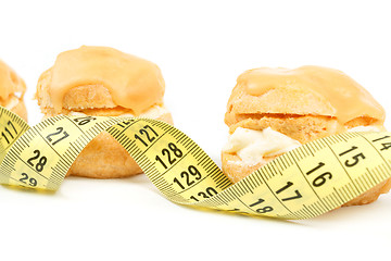 Image showing concept of slimming, caramel cakes with measuring tape