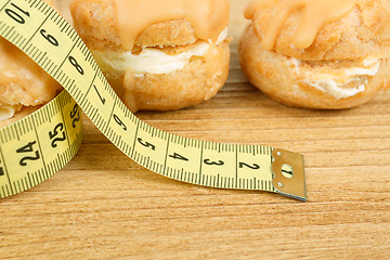 Image showing concept of slimming, closeup of caramel cakes with measuring tape