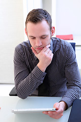 Image showing Man concentrating as he reads his tablet screen