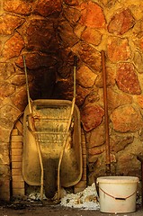 Image showing Old wheelbarrow against stone wall