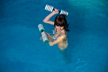 Image showing Attractive girl trains in aqua aerobics