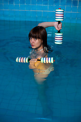 Image showing Attractive girl trains in aqua aerobics