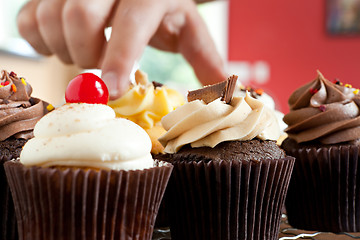 Image showing Hand Grabbing a Gourmet Cupcake