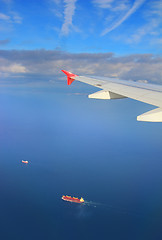 Image showing cargo ships under wing of flying plane