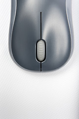 Image showing A wireless mouse positioned vertically on the cover of a laptop