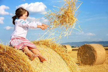 Image showing small rural girl on harvest field with straw bales