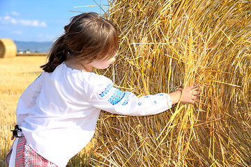 Image showing small rural girl on harvest field with straw bales