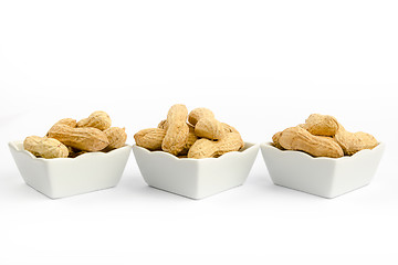 Image showing Three white bowls filled with peanuts on a white background