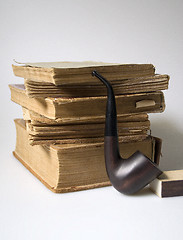 Image showing Stack of old books and a pipe