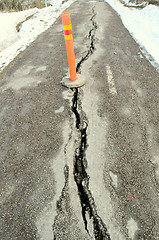 Image showing long crack stretching cross the sidewalk  with orange sign