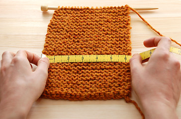 Image showing Two hands measuring knitting in inches