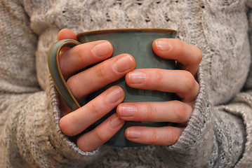 Image showing Two hands holding a mug of drink